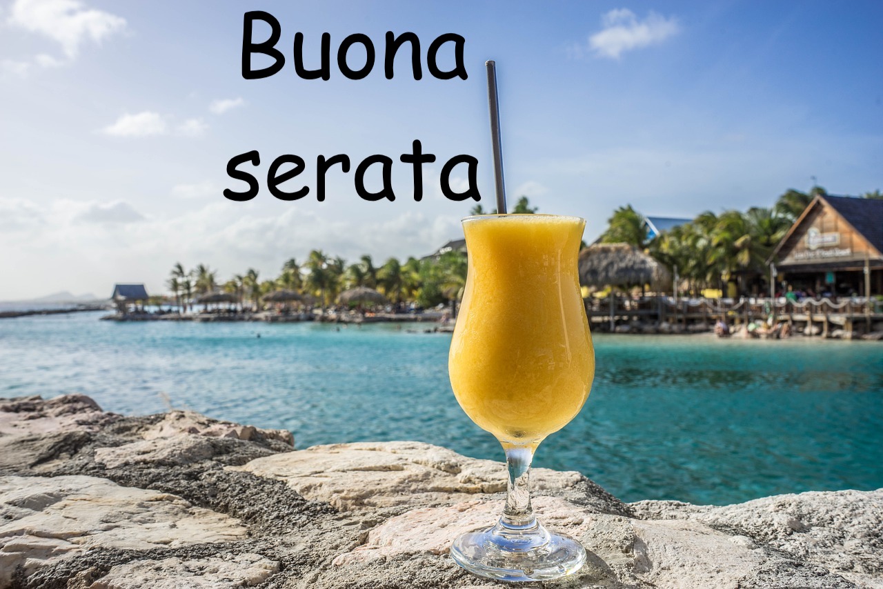 bicchiere con aperitivo o succo di frutta poggiato sulle rocce dietro il mare
 